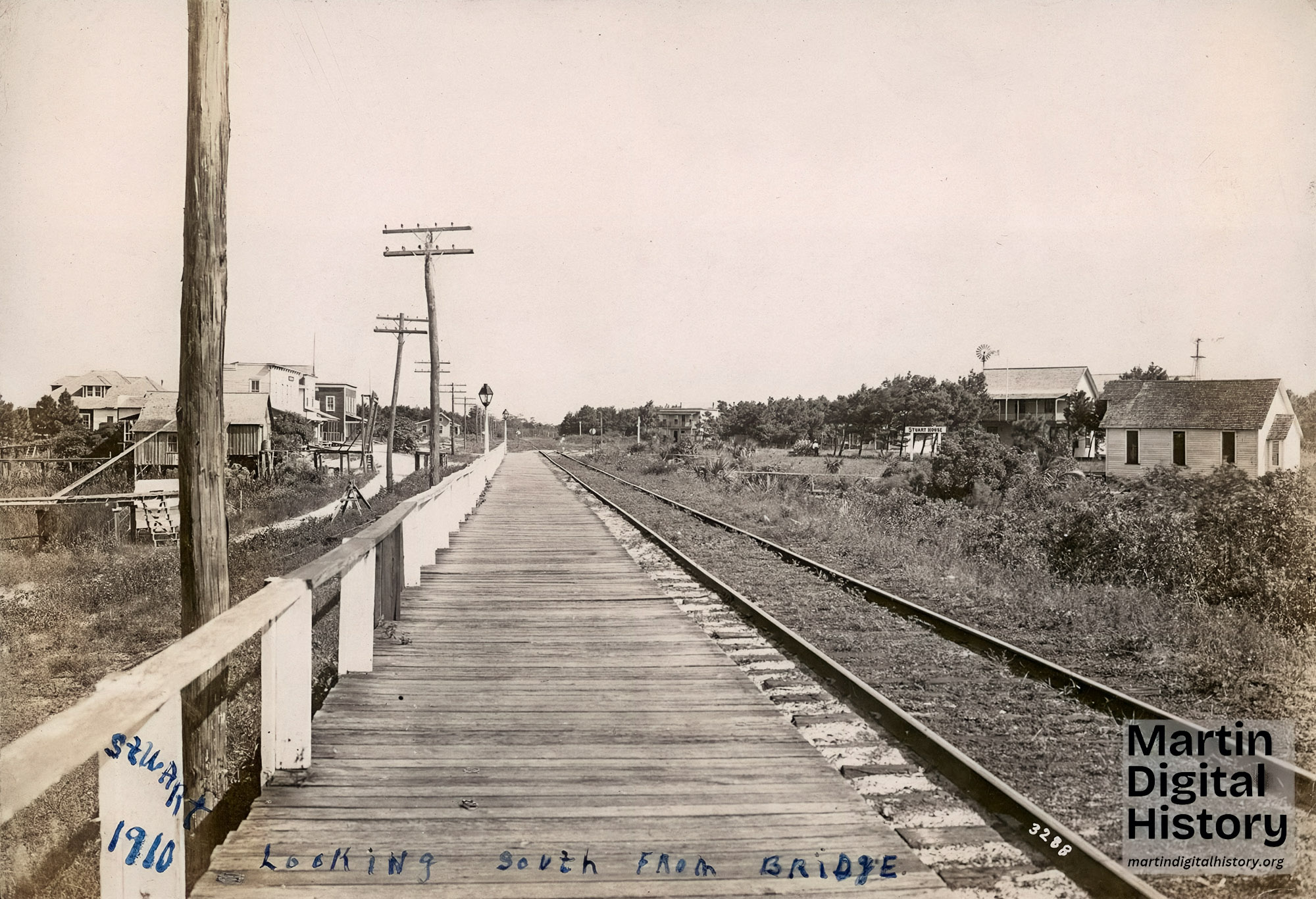 C. 1910. View of Flagler Avenue in Stuart, looking south from near the river. Visible are, on the left, a small railroad building, Stanley Kitching store, Geo. W. Parks (later the Stuart Heritage Museum), and the post office. On the right side is the Stuart House hotel and the building which was formerly the first church, without its steeple. The 1895 Church of StuArt, historical building of the Pioneer Church
